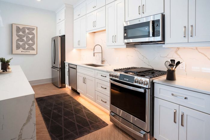 Modern kitchen with sleek white cabinetry, high-end stainless steel appliances, and elegant marble countertops.