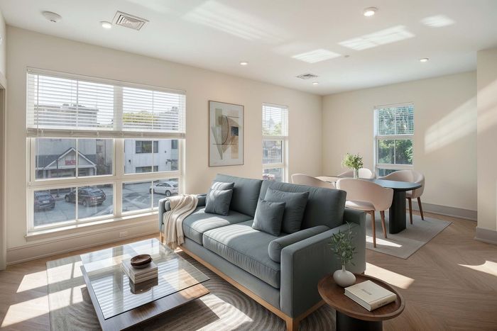 Bright and inviting living room with modern decor, featuring a cozy gray sofa, chic dining area, and large windows enhancing natural light.