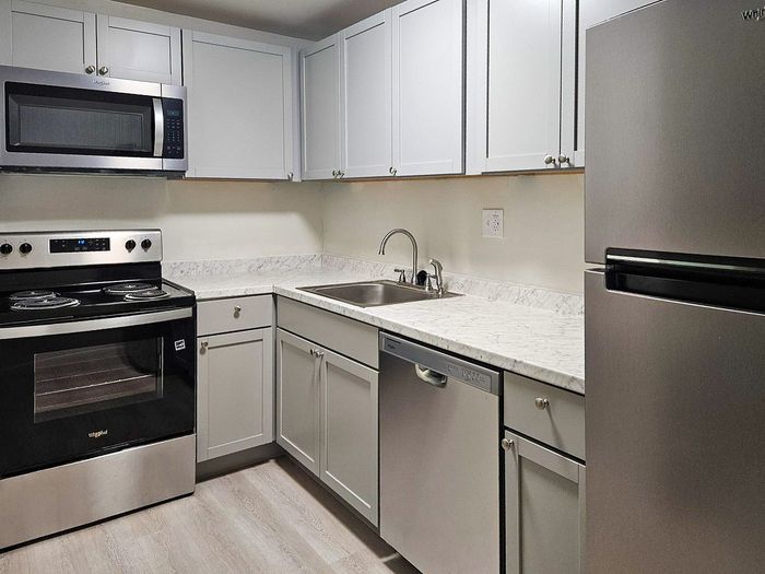 Modern kitchen with sleek stainless steel appliances, elegant marble countertops, and pristine white cabinetry.