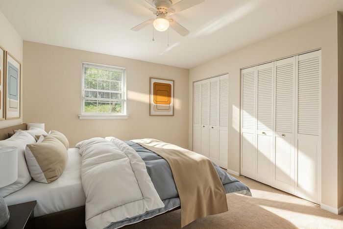 Bright and cozy bedroom with soft neutral tones, featuring a plush bed, large window, modern art, and spacious closet.
