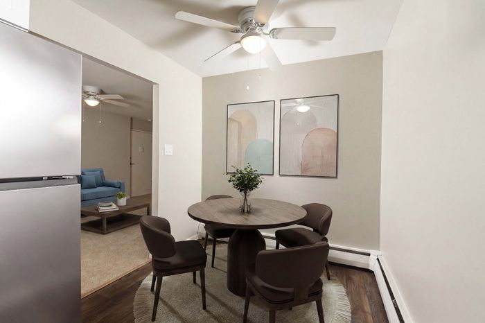 Chic dining area in modern apartment, featuring stylish round table, elegant chairs, and soothing wall art with a view into a cozy living space.