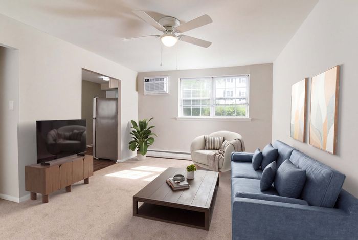Bright and inviting living room with elegant blue sofa, modern coffee table, and large sunlit window, offering a cozy atmosphere.