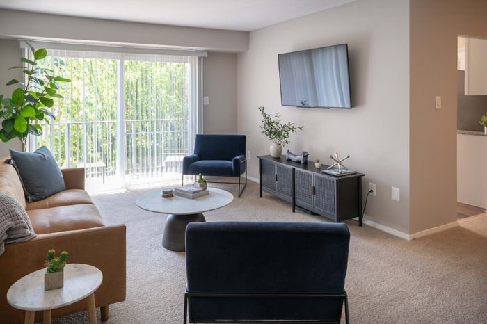 Bright and inviting living room with modern furniture, large windows, and lush garden views.