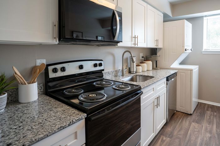 Modern kitchen with granite countertops, sleek appliances, and integrated laundry area, offering a stylish and functional space.