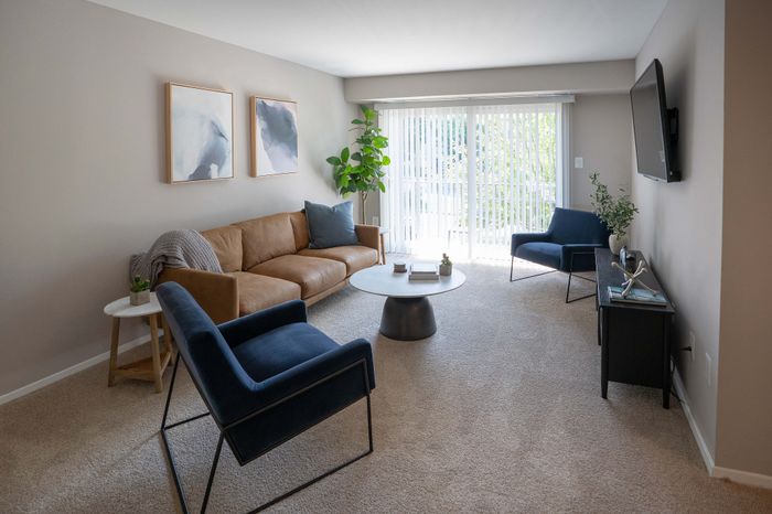 Bright and inviting living room with modern decor, featuring a comfortable leather sofa, elegant armchairs, and a large window with natural light.
