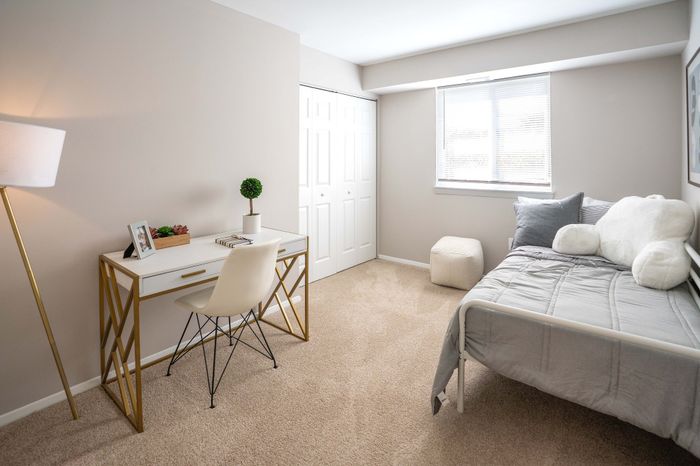 Bright and cozy bedroom featuring a sleek writing desk, modern chair, and inviting bed with plush pillows.