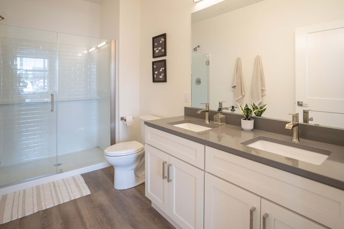 Elegant modern bathroom with dual sinks, sleek countertops, and glass-enclosed shower, offering a fresh and airy feel.