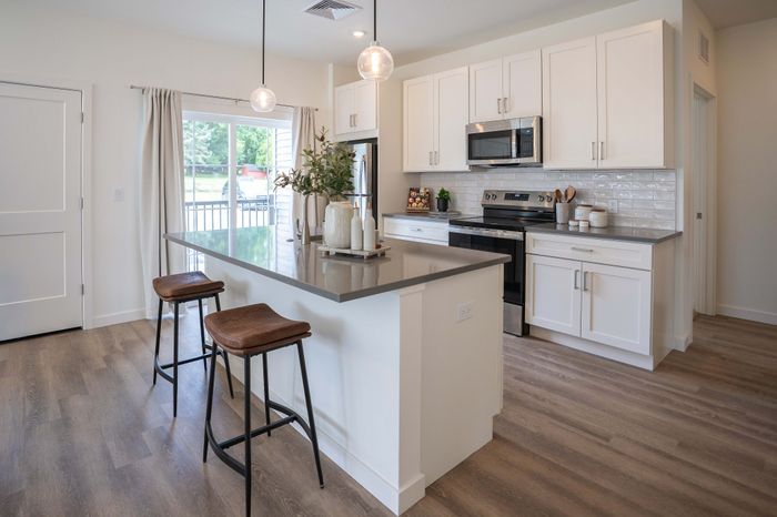 Modern kitchen with sleek countertops, white cabinetry, and elegant bar stools under pendant lighting.