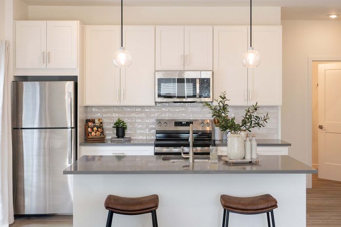 Contemporary kitchen with sleek stainless steel appliances, elegant pendant lighting, and a stylish breakfast bar with seating.