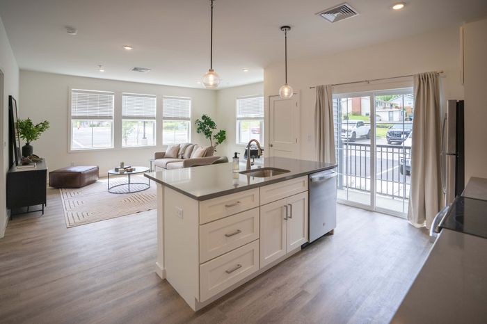 Bright and modern open-concept living space with sleek kitchen island, inviting lounge area, and large windows offering natural light.