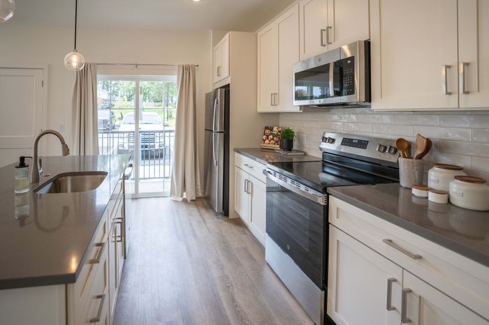 Modern kitchen with sleek countertops, stainless steel appliances, and large windows providing natural light.