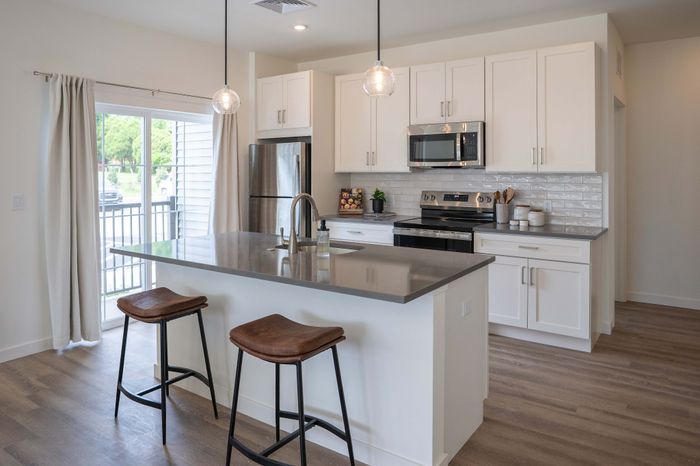 Modern kitchen with sleek countertops, stainless steel appliances, and stylish pendant lighting, creating a bright and welcoming space.