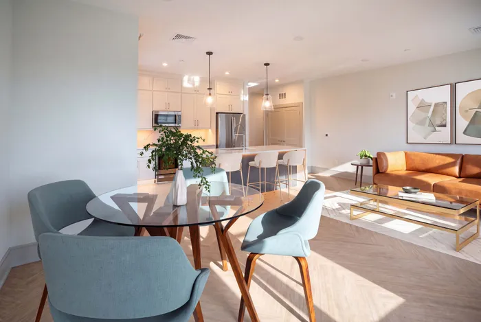 Bright and modern open-concept living space featuring a stylish kitchen with bar seating, elegant dining area, and inviting leather sofa.
