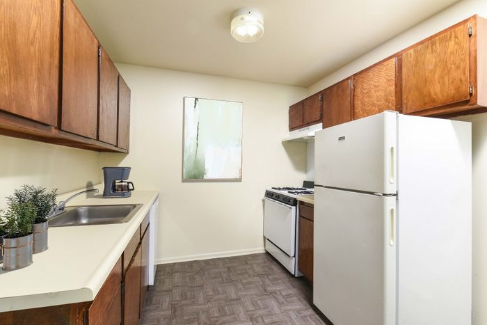 Charming apartment kitchen with sleek countertops, classic wooden cabinets, and modern appliances for a cozy cooking experience.