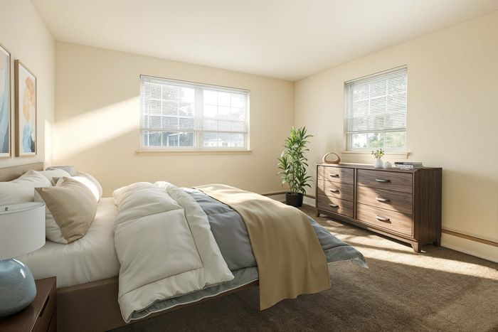 Sunlit bedroom featuring a cozy queen-sized bed, modern chest of drawers, and lush green plant.