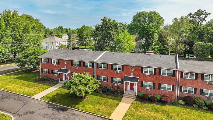 Charming red-brick apartment complex surrounded by lush greenery and open spaces, featuring a classic and inviting design.