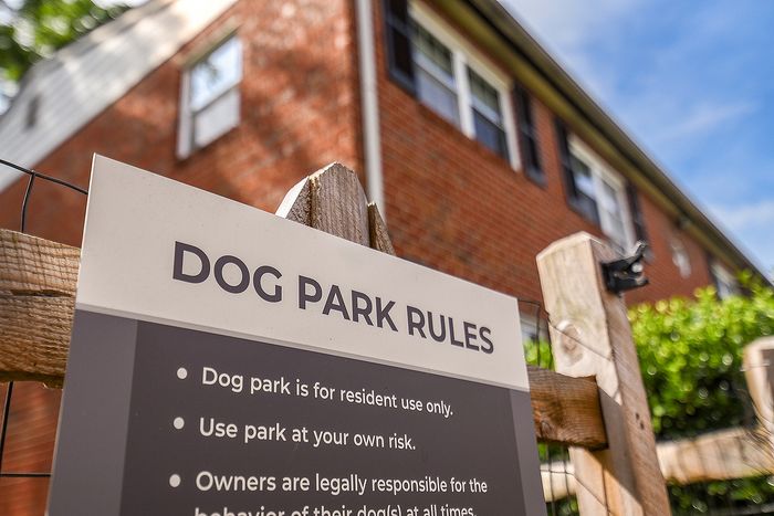 Charming brick apartment exterior with a nearby dog park, perfect for pet-friendly living.