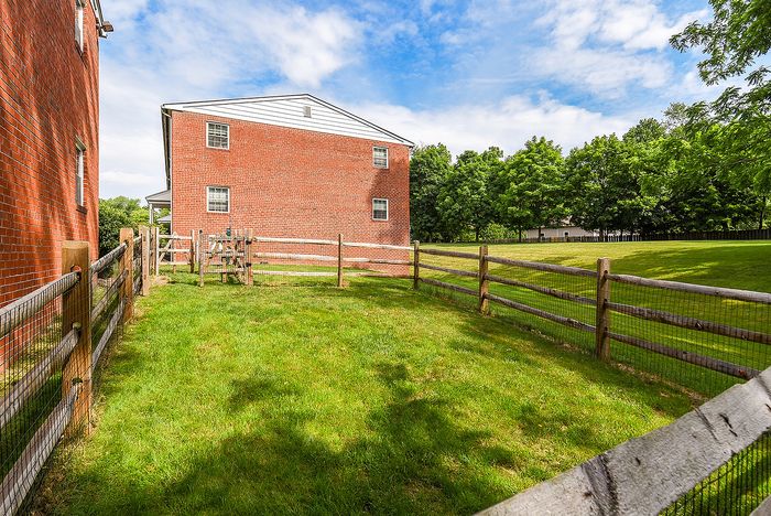 Charming red brick building surrounded by lush green lawns and rustic wooden fences, offering a serene and welcoming atmosphere.