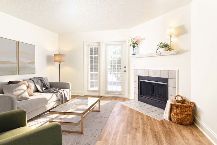 Elegant living room with cozy fireplace, bright natural light through French doors, modern sofa, and chic decor.