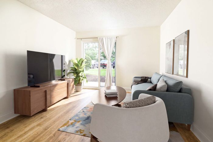 Bright and modern living room with a large flat-screen TV, stylish furniture, and floor-to-ceiling windows for natural light.