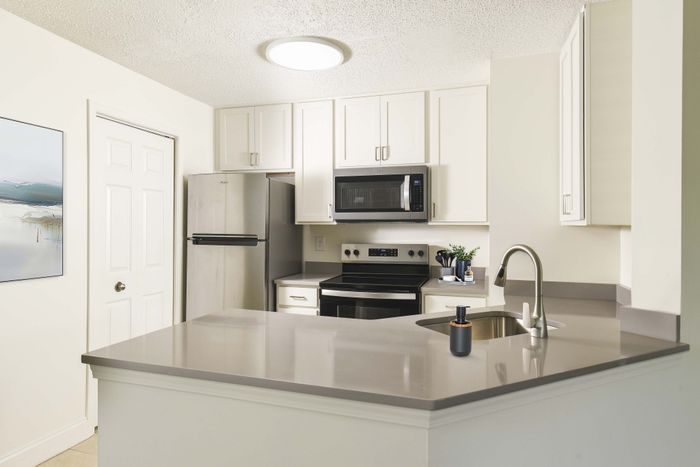 Modern kitchen with sleek stainless steel appliances, elegant white cabinetry, and a stylish grey countertop, perfect for entertaining.