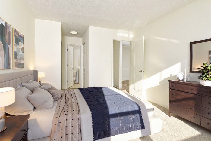 Bright and inviting bedroom with plush bedding, modern decor, and ample natural light, perfect for relaxation.