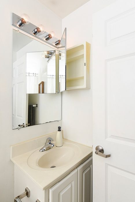 Bright bathroom with elegant lighting, sleek sink, and mirrored cabinet offering a modern touch.