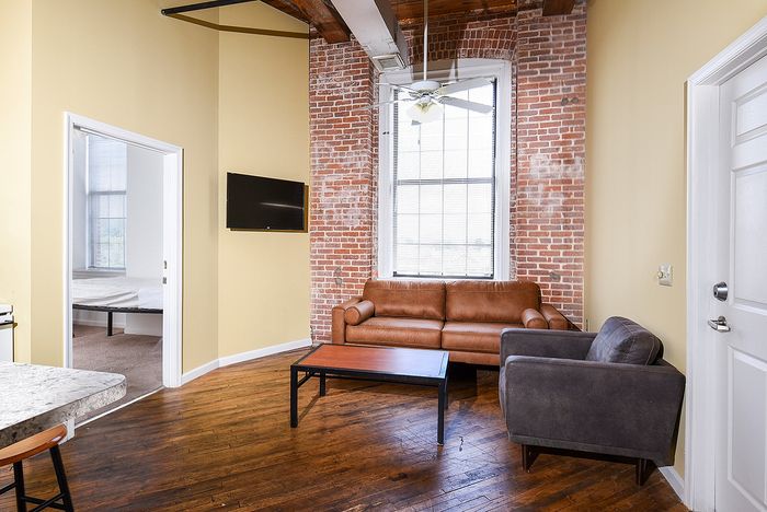 Charming apartment living room with exposed brick walls, modern furnishings, and natural light, offering a cozy and inviting atmosphere.