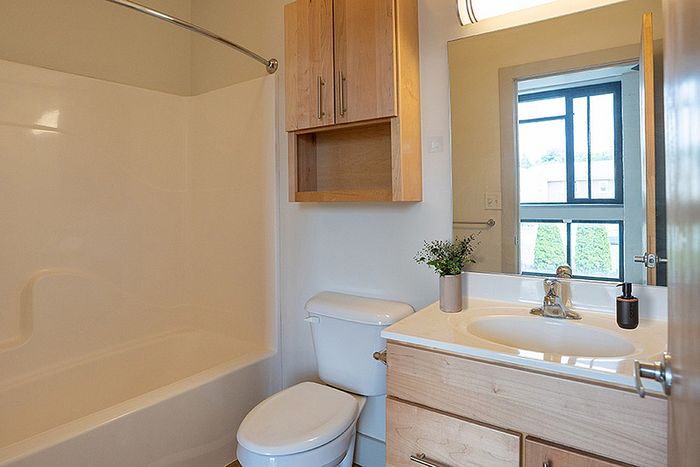 Bright and modern bathroom featuring elegant cabinetry, a sleek sink, and a large mirror, offering a welcoming and refreshing space.