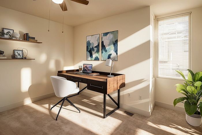 Inviting home office with modern desk, plush chair, and abundant natural light, featuring elegant decor and a green plant for a refreshing atmosphere.