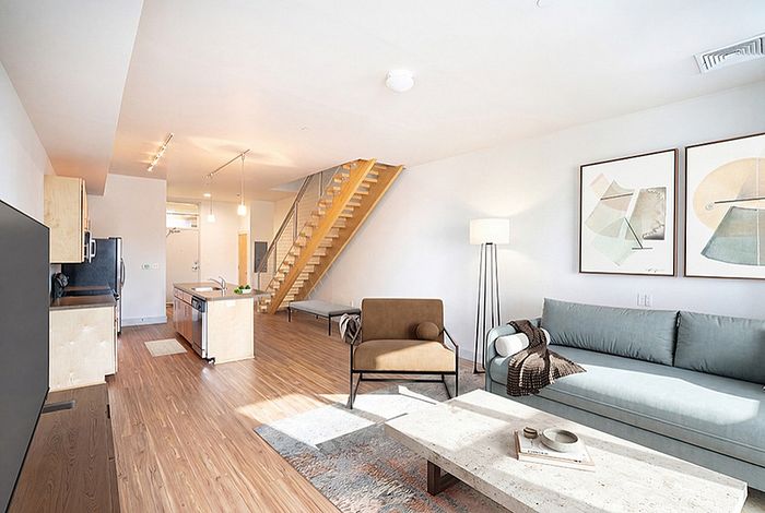 Bright, modern living space featuring an open-concept kitchen and living room, elegant wooden staircase, and stylish contemporary decor.