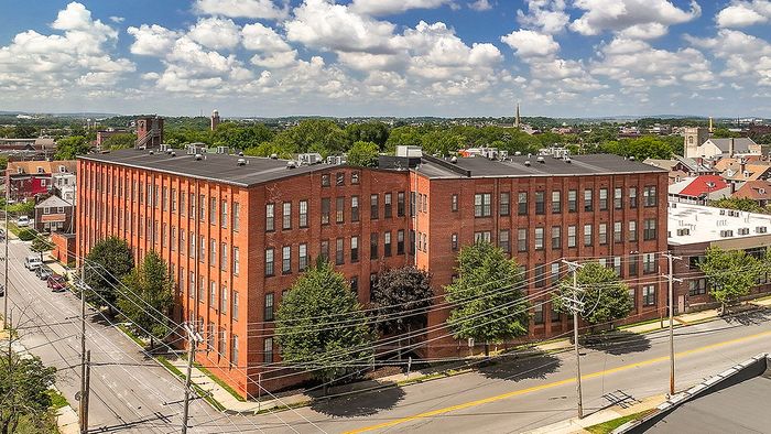 Charming red brick apartment complex with lush surroundings, offering modern living in a historic setting and stunning views of the city skyline.