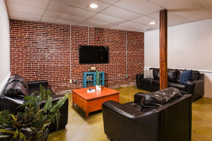 Chic living space with exposed brick wall, sleek black leather sofas, and a stylish coffee table, perfect for relaxation and entertainment.