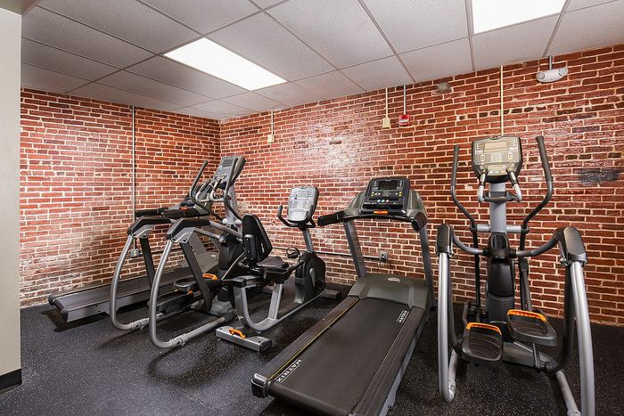 Chic fitness room with modern exercise equipment against a stylish exposed brick wall.