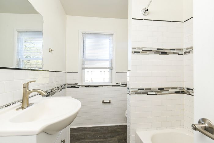 Bright and modern bathroom featuring elegant white tilework, a sleek sink, and natural light filtering through the window.
