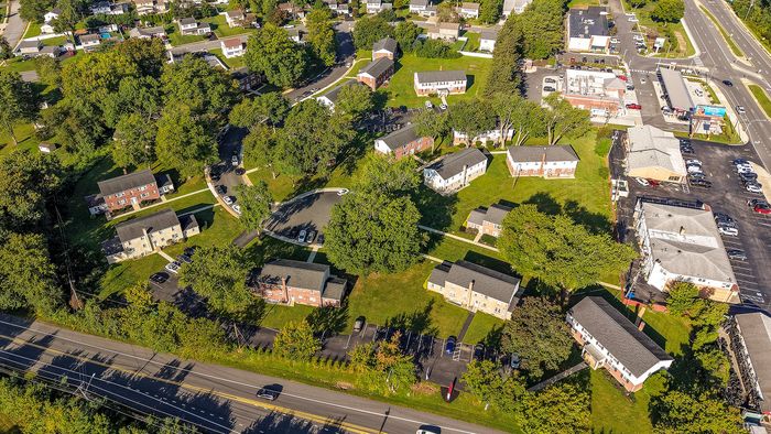 Aerial view of a charming residential neighborhood featuring lush green lawns, tree-lined streets, and cozy homes nestled within a vibrant community.