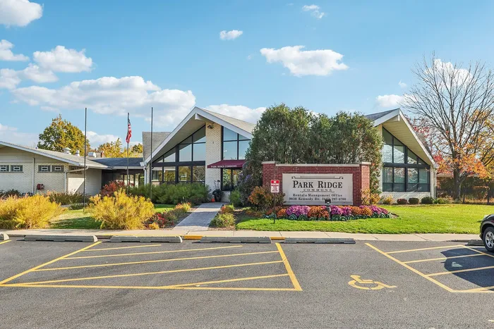 Charming Park Ridge Commons building showcasing modern architecture with lush landscaping and vibrant autumn colors under a clear blue sky.
