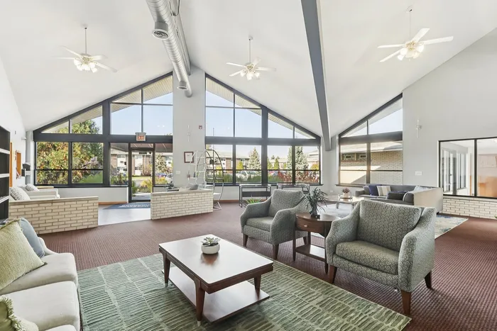 Bright and welcoming living space featuring modern furniture, expansive windows, and a vaulted ceiling for an open, airy atmosphere.