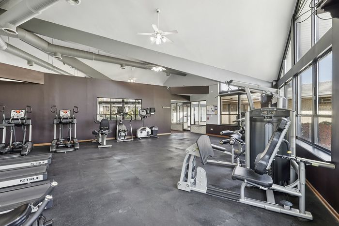 Spacious fitness center with modern cardio and strength-training equipment, featuring large windows for natural light.