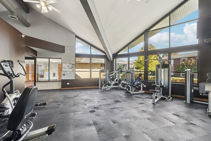 Bright, spacious gym with modern exercise equipment and large windows offering scenic outdoor views.