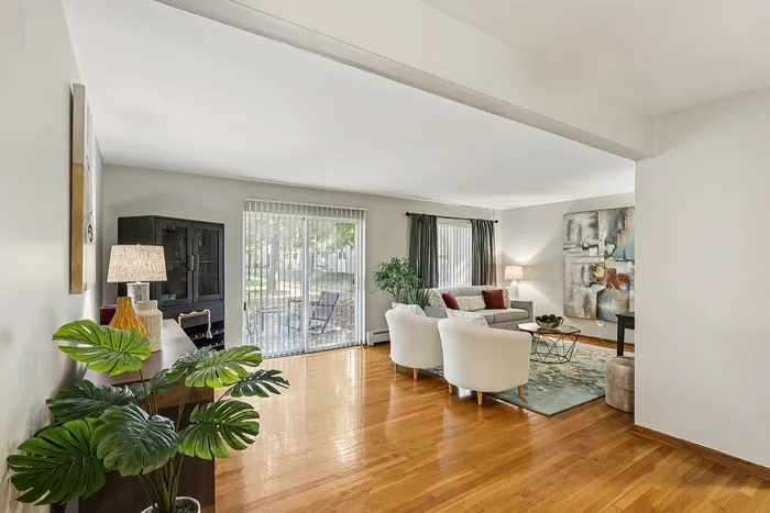 Bright and inviting living room with hardwood floors, plush seating, and modern decor, featuring a large window with a serene view of nature.