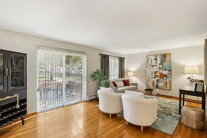 Inviting living room with elegant decor, featuring a cozy seating area, contemporary artwork, and large glass doors opening to a scenic outdoor view.
