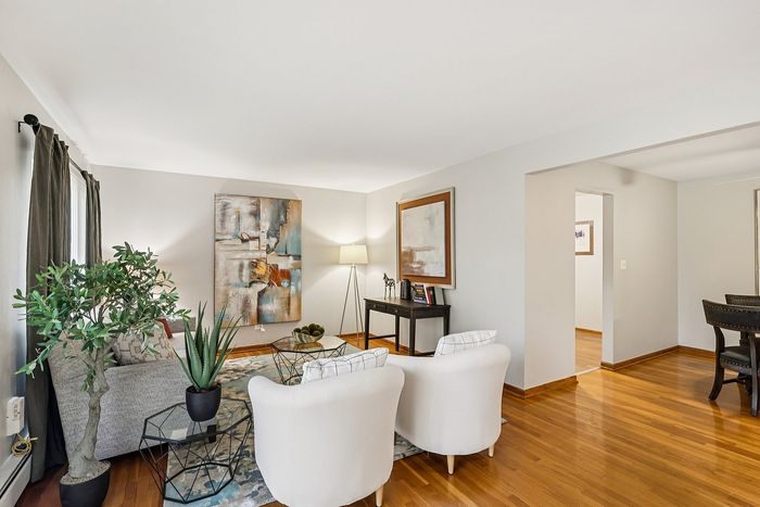 Bright, inviting living room with stylish artwork, cozy seating, and elegant hardwood floors.