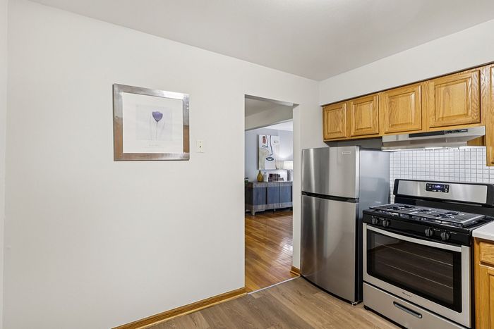 Inviting kitchen with stainless steel appliances, wooden cabinets, and a charming view into a cozy living space.