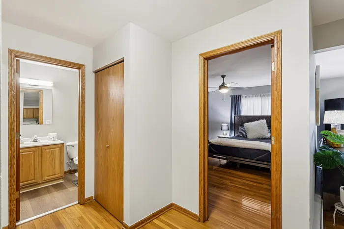Inviting hallway with wooden accents leading to a cozy bedroom and a well-lit bathroom, perfect for modern living.
