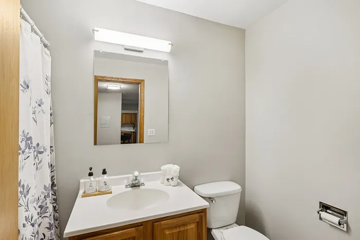 Bright, modern bathroom featuring sleek wood cabinets, elegant decor, and a stylish floral shower curtain.