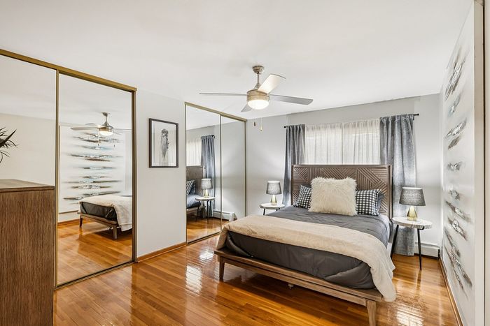 Elegant bedroom featuring mirrored closets, stylish decor, and a cozy bed with plush pillows, creating a serene retreat.