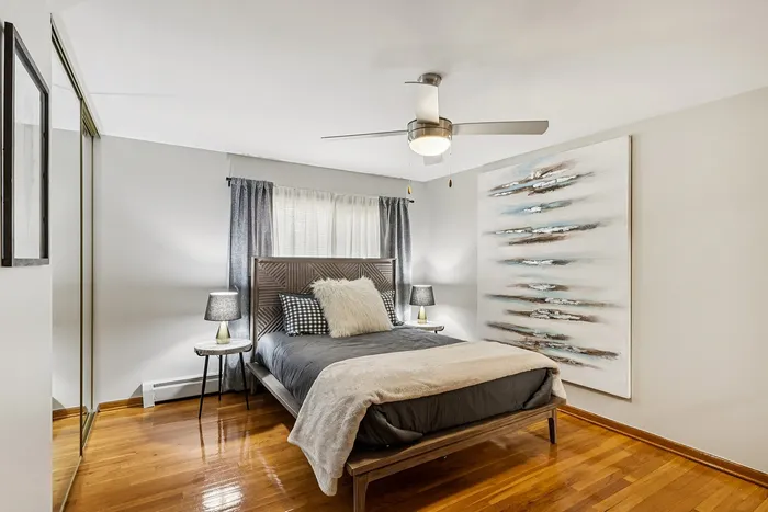 Contemporary bedroom with stylish decor, featuring elegant hardwood floors, cozy bedding, and chic artwork for a sophisticated ambiance.