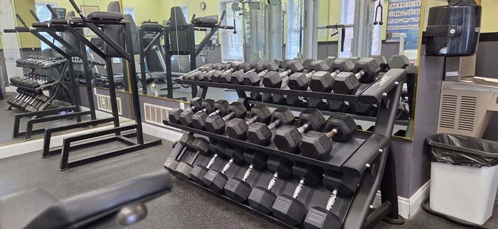 Modern gym facility featuring a range of dumbbells on a sleek rack, mirrored walls, and fitness machines creating an inviting workout space.