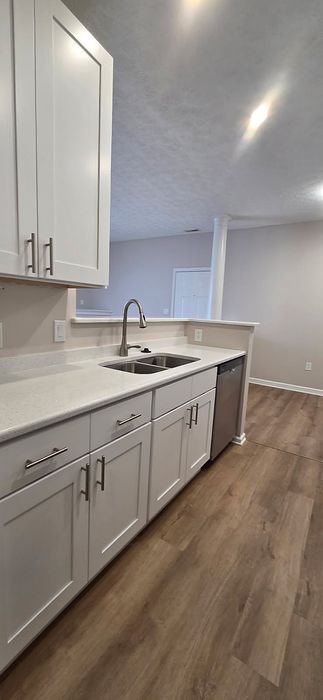 Modern kitchen with elegant white cabinetry, sleek countertops, and stainless steel appliances in an open-concept layout.